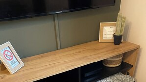 Un mobile in legno con un televisore montato, un cartello che indica la disponibilità del WiFi e un piccolo cactus sopra.