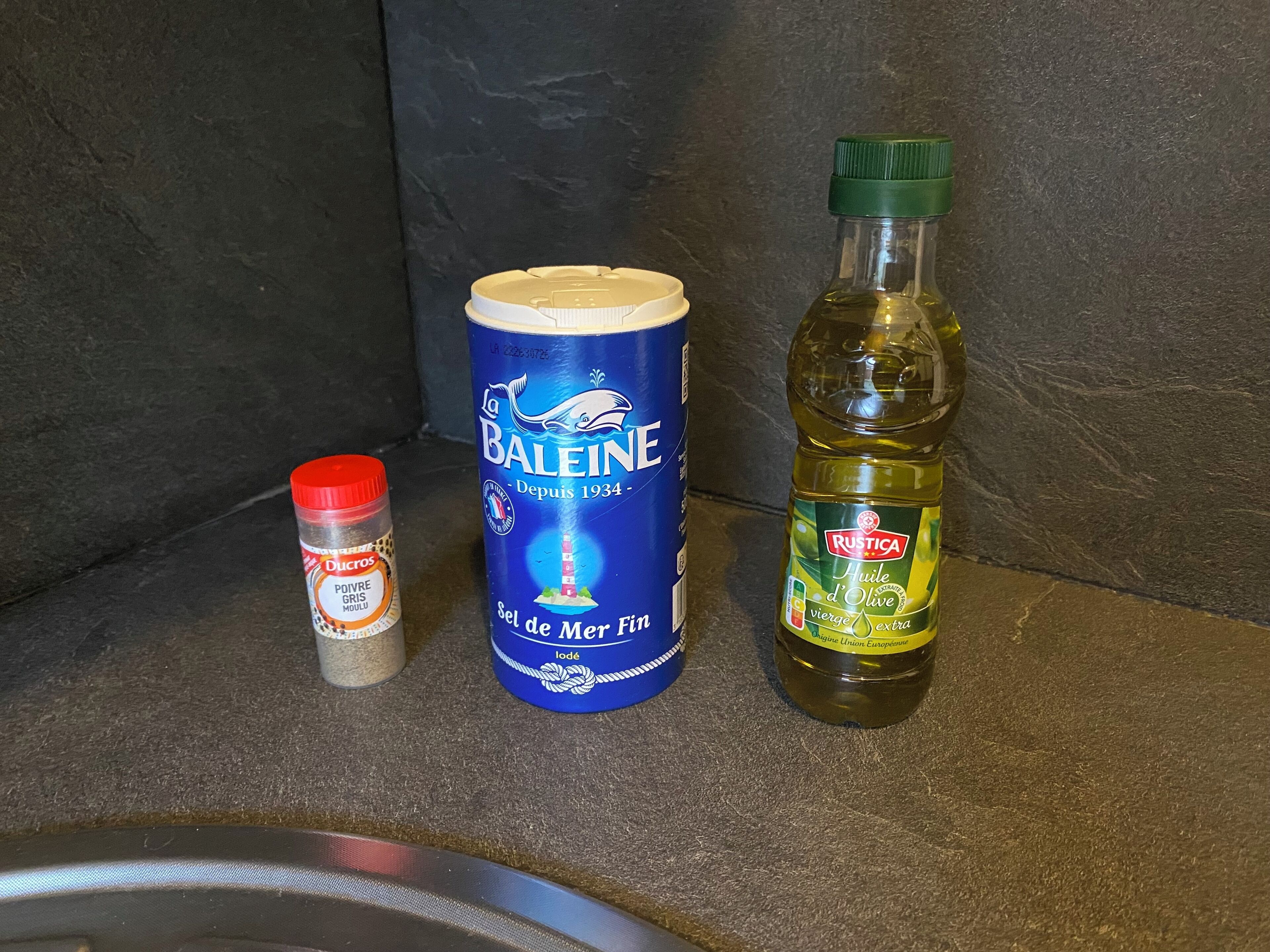 Una lata de Balée, una botella de aceite y un frasco de especias sobre una encimera de cocina.