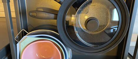 A kitchen with a stove, a frying pan, and a pink pot.