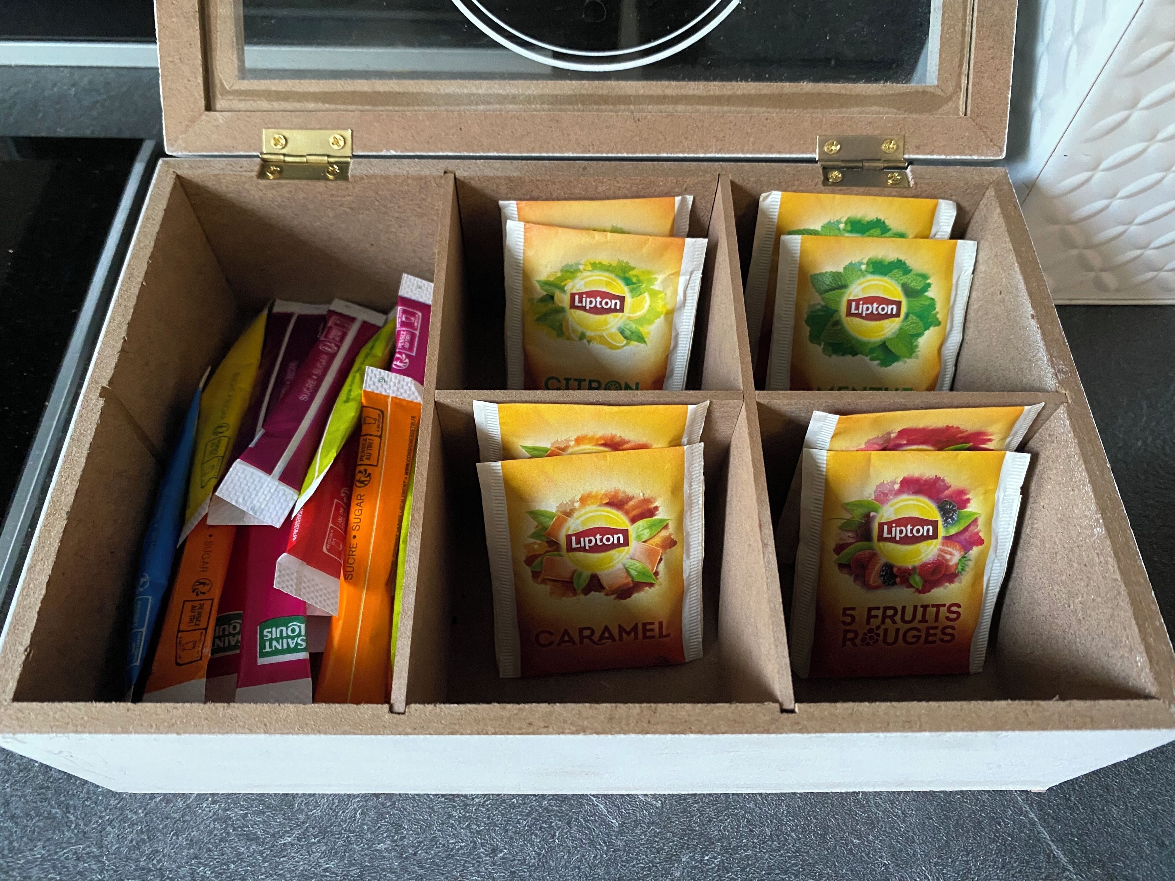 A box containing Lipton tea bags in various flavors, including caramel and 5 fruits & juices, and some books.
