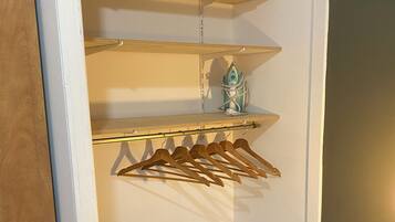 A storage closet with wooden shelves, a hanging rack, and a black storage box.