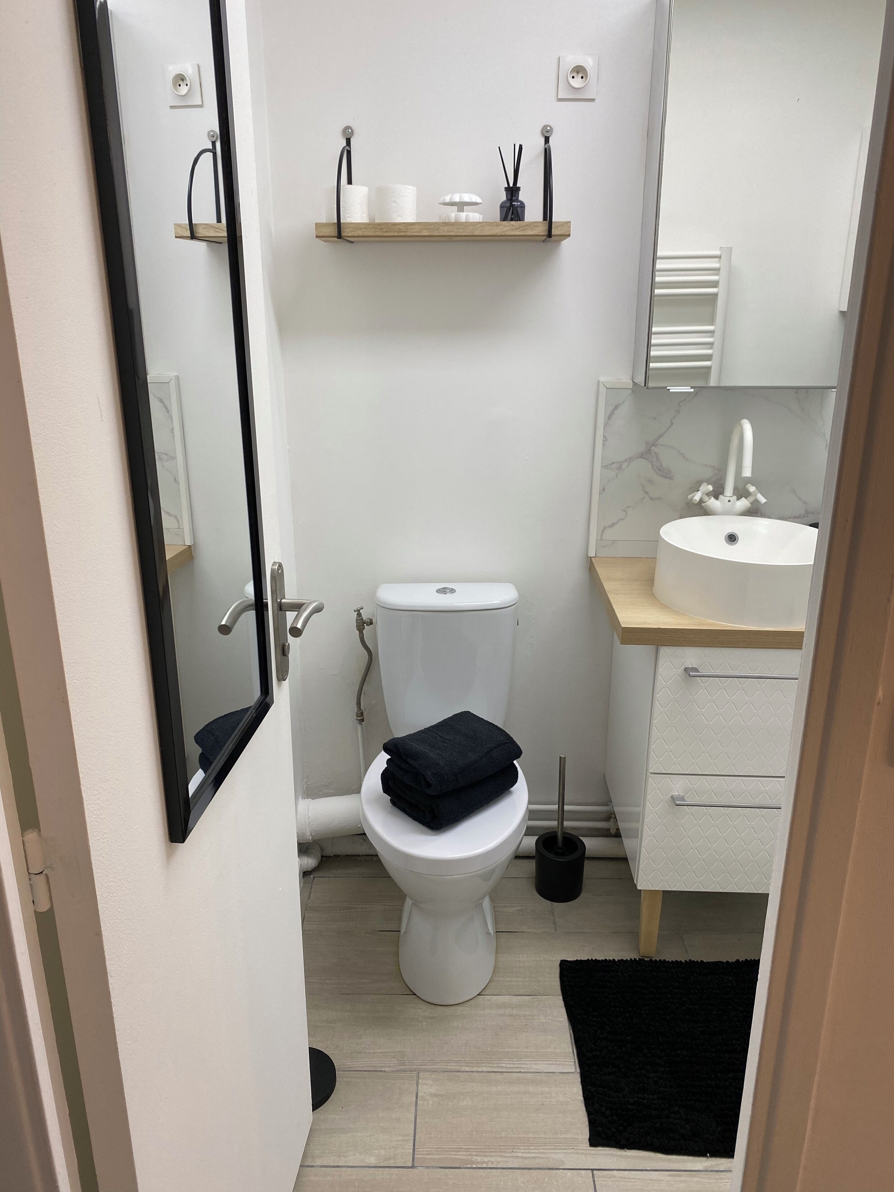 Ein kleines Badezimmer mit Toilette, Waschbecken und Spiegel.
