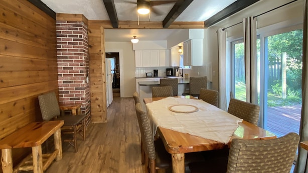 A wooden dining area with a table and chairs, a brick wall, and a ceiling fan. - Historic Lake Roosevelt Home (Kettle Falls)