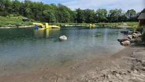 Un río tranquilo con aguas cristalinas, rodeado de vegetación y una pequeña estructura de madera a la derecha.