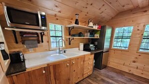 Una cocina compacta con armarios de madera, un lavamanos, un microondas y un refrigerador.