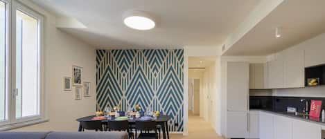 A modern apartment with a dining area, kitchen, and a hallway leading to another room.