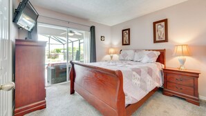 Ein Schlafzimmer mit Bett, Nachttischen, einem Fernseher und Blick durch eine Glastür.