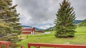 Un paisaje rural con un granero rojo, un abeto y un campo cubierto de hierba.