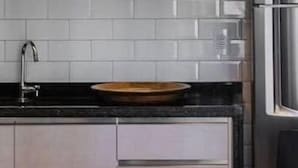 A modern kitchen with a stainless steel refrigerator, a white pendant light, and a black countertop. - Hy Beach Flats - Santa Maria (Recife)