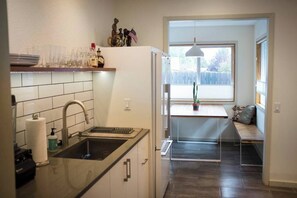 Enjoy meal preparation and dining in this kitchen with an oven and sink, complemented by a dining area with a bench and table.
