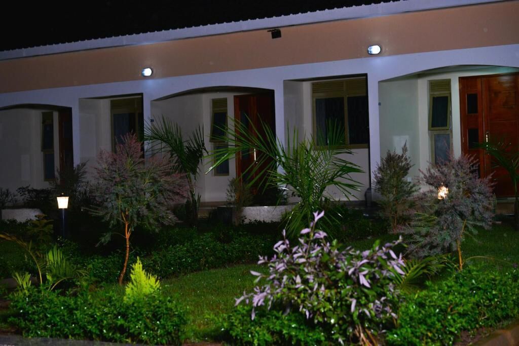 Un hotel con diverse camere, ognuna dotata di porta e finestre. Le camere sono disposte in fila, con un giardino di fronte.
