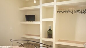Une chambre à coucher avec un lit, un téléviseur posé sur une étagère et un sol à motifs.
