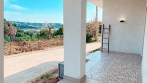 Un espace extérieur abrité, doté d’un sol à motifs, d’une échelle et offrant une vue sur une route et un paysage.
