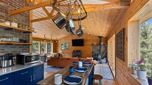 A modern kitchen with a long island, wooden beams, and a stone fireplace. - Enjoy the Now in an Alpine Oasis (Alma)