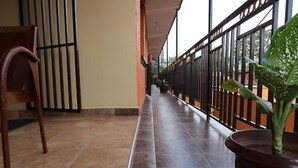 Passadís amb una cadira, una planta en test i una barana que dona a l'exterior.