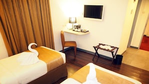 A hotel room with two beds, a desk, a chair, and a television. - MV Orienchi (Jakarta)