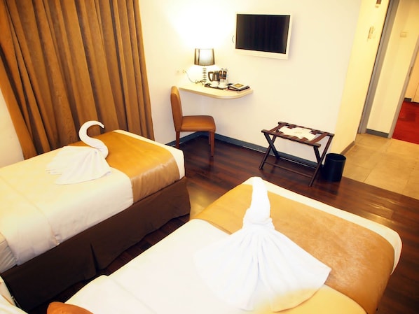 Una habitación de hotel con dos camas, un escritorio, una silla y un televisor.