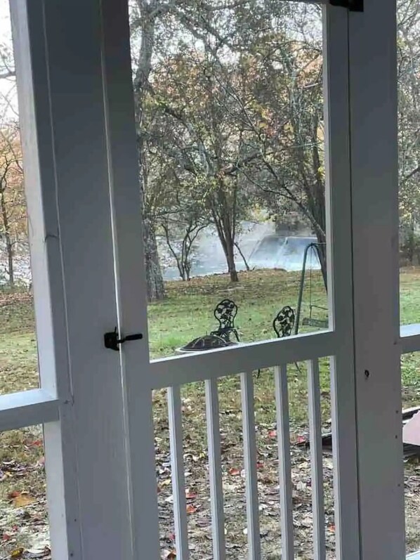 A view through a white-framed door with a metal railing, leading to an outdoor area with trees and a grassy lawn. - Sparta House on the Calfkiller River
(Sparta)