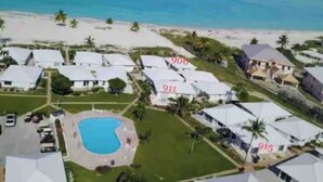 An aerial view of a resort with numbered villas, a swimming pool, and a beach in the background. - Sea Biscuit Ocean Villa 911 (Abaco)