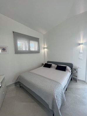 A bedroom with a bed, bedside tables, a window, and wall-mounted lighting. - Villa Giuliana luxury home: swimming pool, solarium, barbecue. A few steps from the sea (Fontane Bianche)