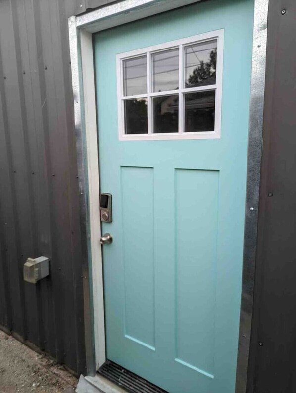 Una puerta verde aguamarina con un pequeño ventanal y un timbre.