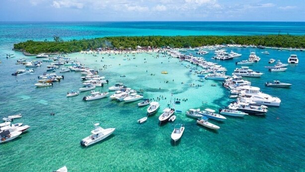 Un port de plaisance où de nombreux bateaux sont amarrés et où se trouvent des personnes sur la rive.