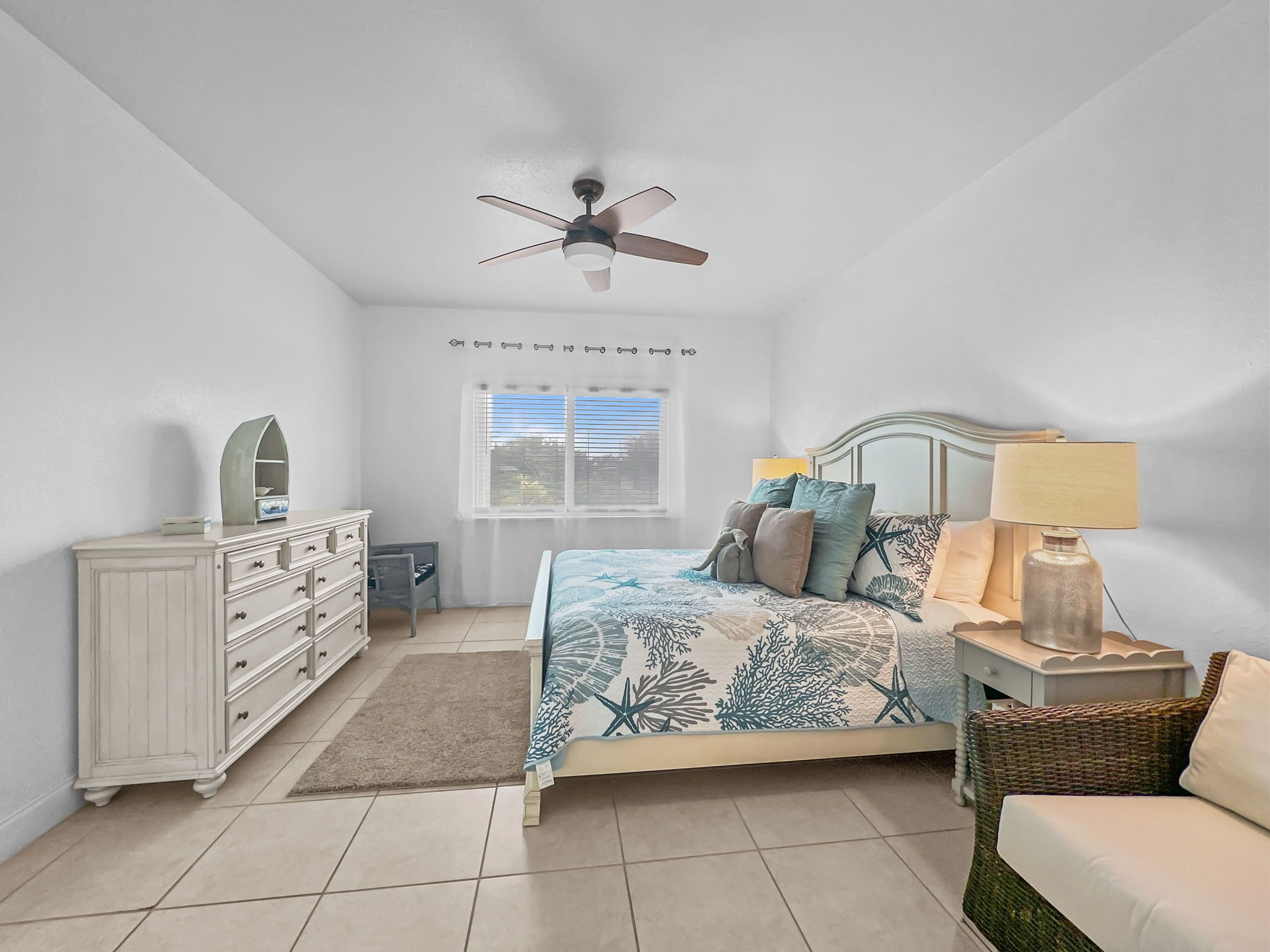 A bedroom with a bed, dresser, nightstand, lamp, and ceiling fan.