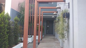 Un edificio moderno con una galería techada, columnas de madera y plantas en macetas.