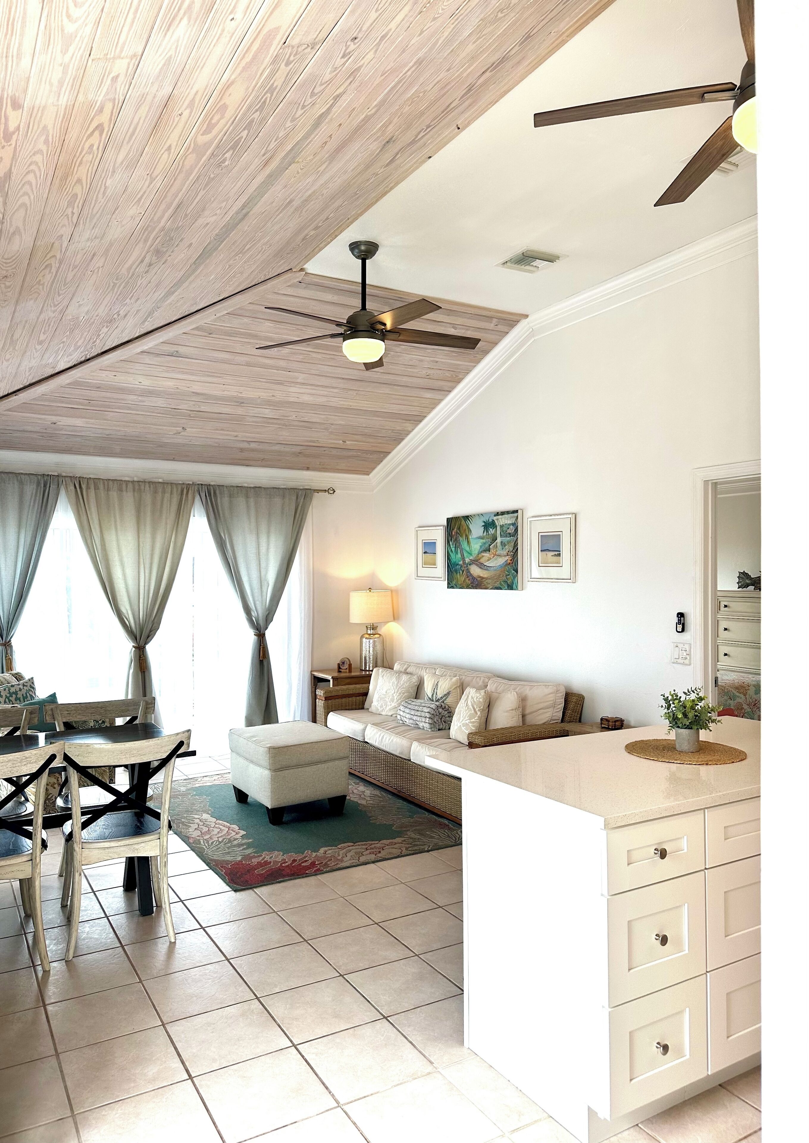 A spacious living area with a high ceiling, a dining table, a sofa, and a kitchen island.