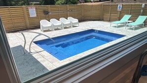 A swimming pool with a glass edge, surrounded by white lounge chairs and a wooden fence. - Florida style  built  2023. Heated pool. Dog park. 10 min walk to beach.  (Southern Shores)