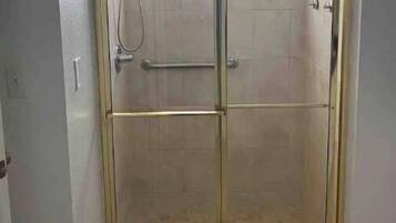 A glass-enclosed shower area with a tiled floor and a small window above the door.