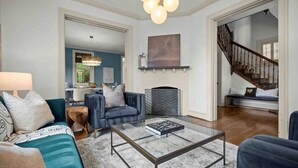 A spacious living room with a modern sofa, a coffee table, and a staircase leading to another level.