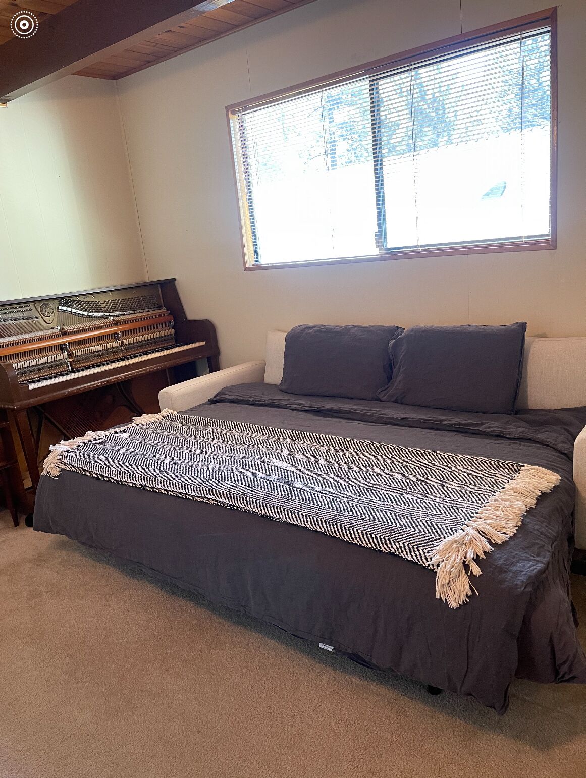 A room with a bed, a piano, and a window with blinds.