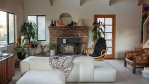 Un salon chaleureux avec une cheminée, un canapé, un fauteuil et des plantes en pot.