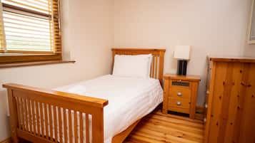 A bedroom with a wooden bed, a bedside table with drawers, a nightstand, and a wardrobe.