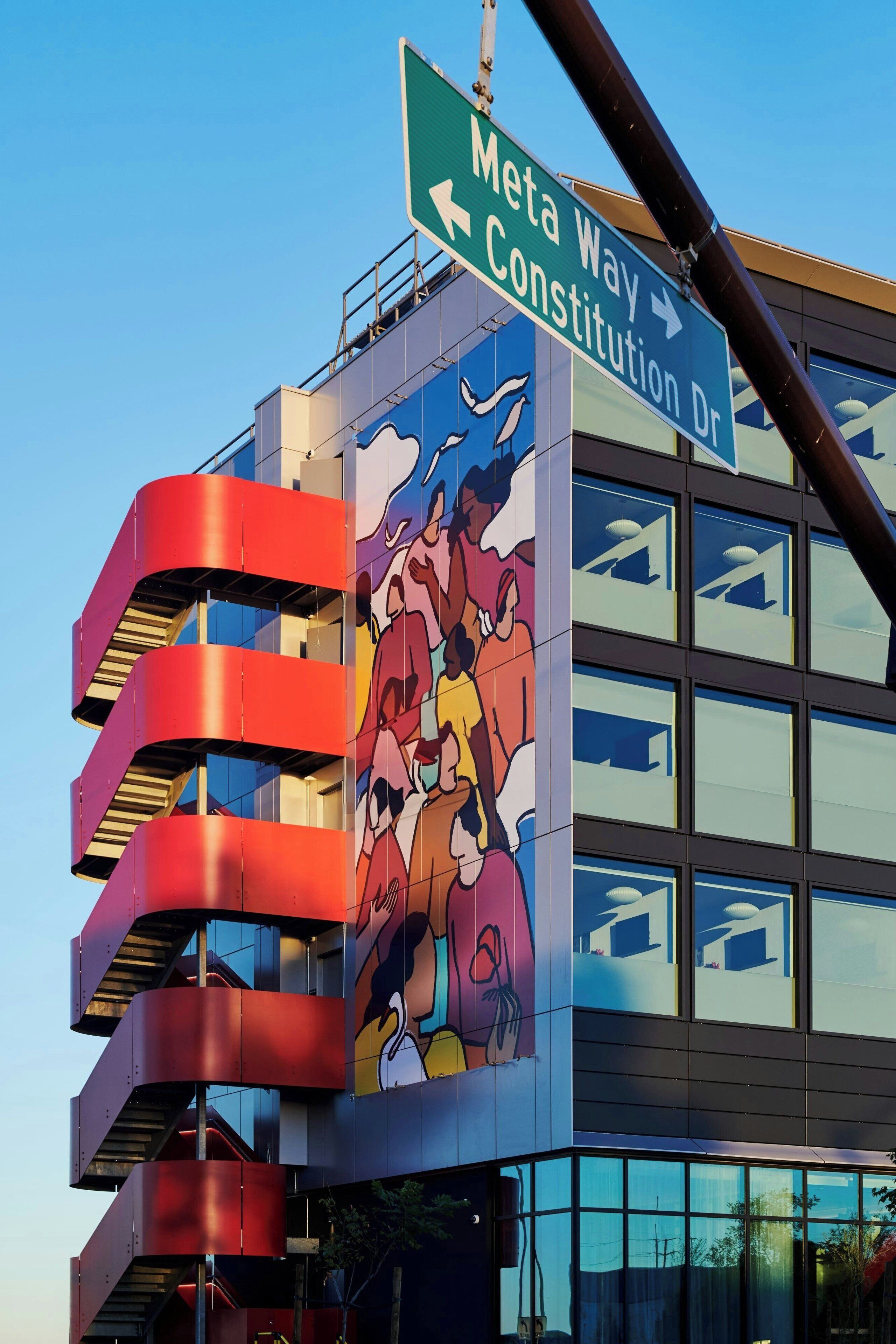A building with a mural of cartoon characters, a sign for Meta Way, and Constitution Dr.