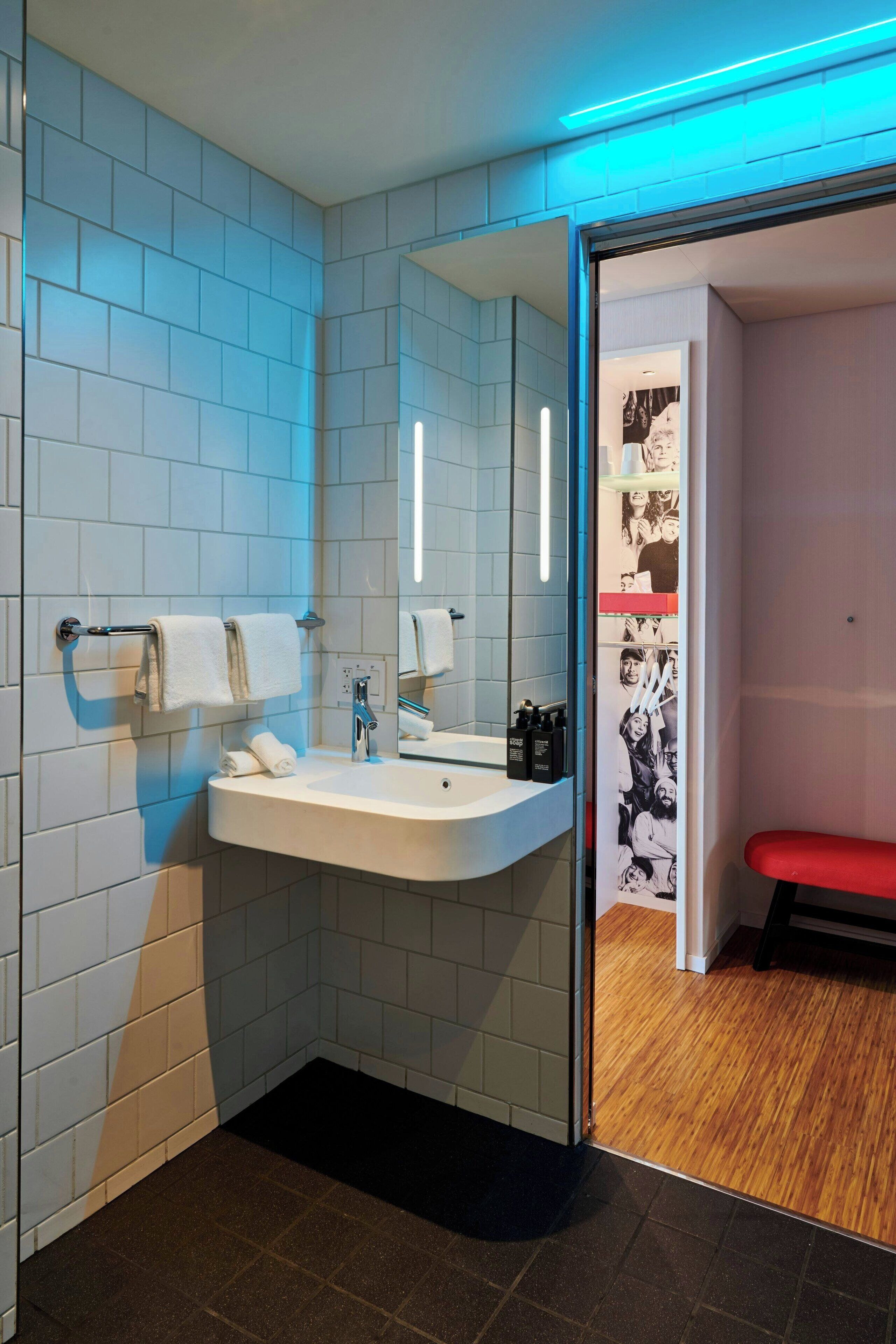 A modern bathroom with a white sink, mirror, and towel rack.