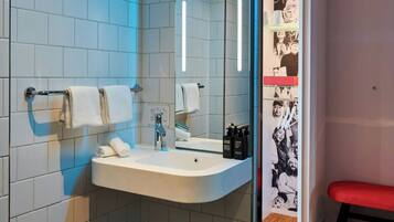 Un baño moderno con lavamanos, espejo y toallero blancos.