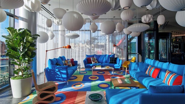 A modern interior with blue sofas, a colorful rug, and white paper lanterns. - citizenM Menlo Park (Menlo Park)