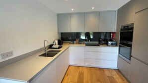 Una cocina moderna con armarios blancos, encimera de madera y electrodomésticos integrados.