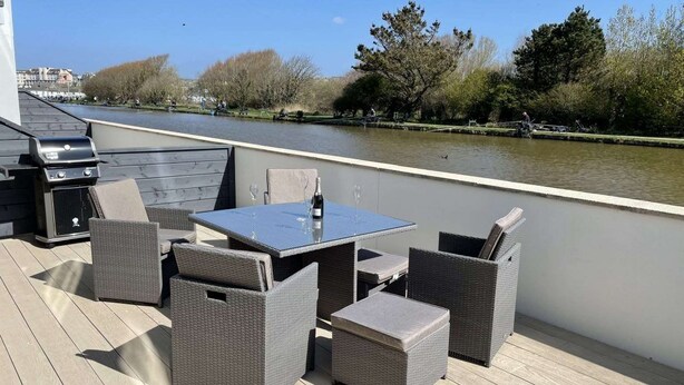 Terraza al aire libre con una mesa y sillas, con vista a un río.