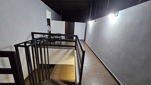 Una escalera con piso de madera y barandillas de metal negro, que conduce a una habitación con pared blanca y una puerta.