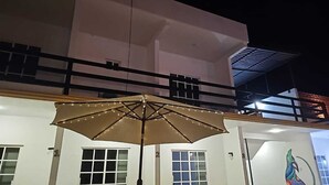 Un edificio con balcón y una gran sombrilla iluminada.