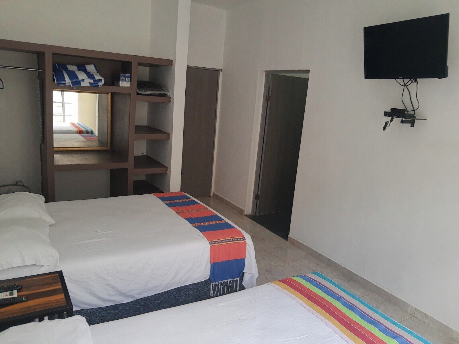 Habitación de hotel con dos camas, un armario, un televisor y una puerta.