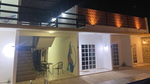 Un edificio moderno con un área exterior cubierta, una escalera y un mural en la pared.