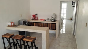 Una cocina con una isla central, taburetes, una cafetera y un fregadero.