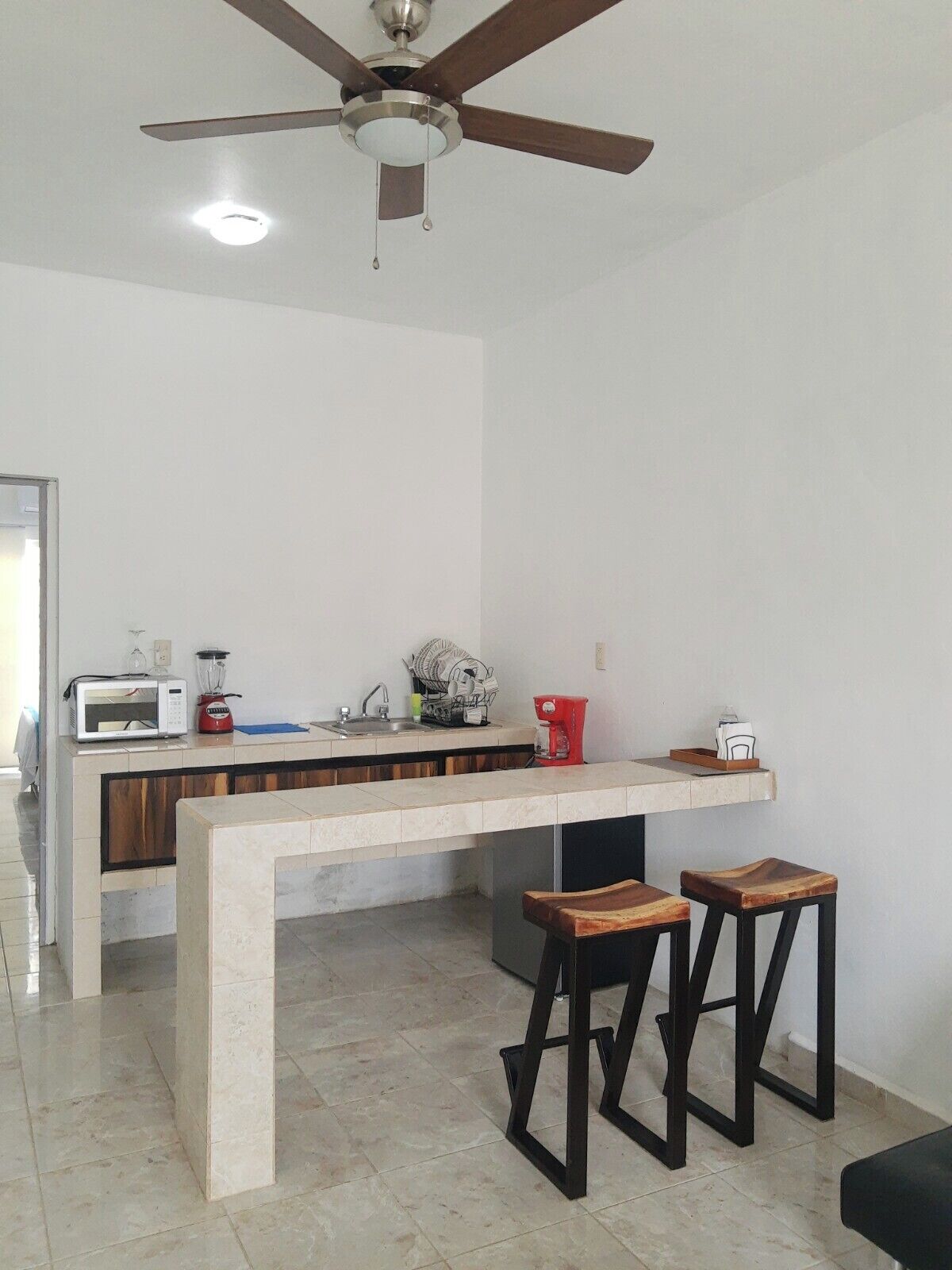 Una cocina moderna con una isla central, un ventilador de techo y un microondas.