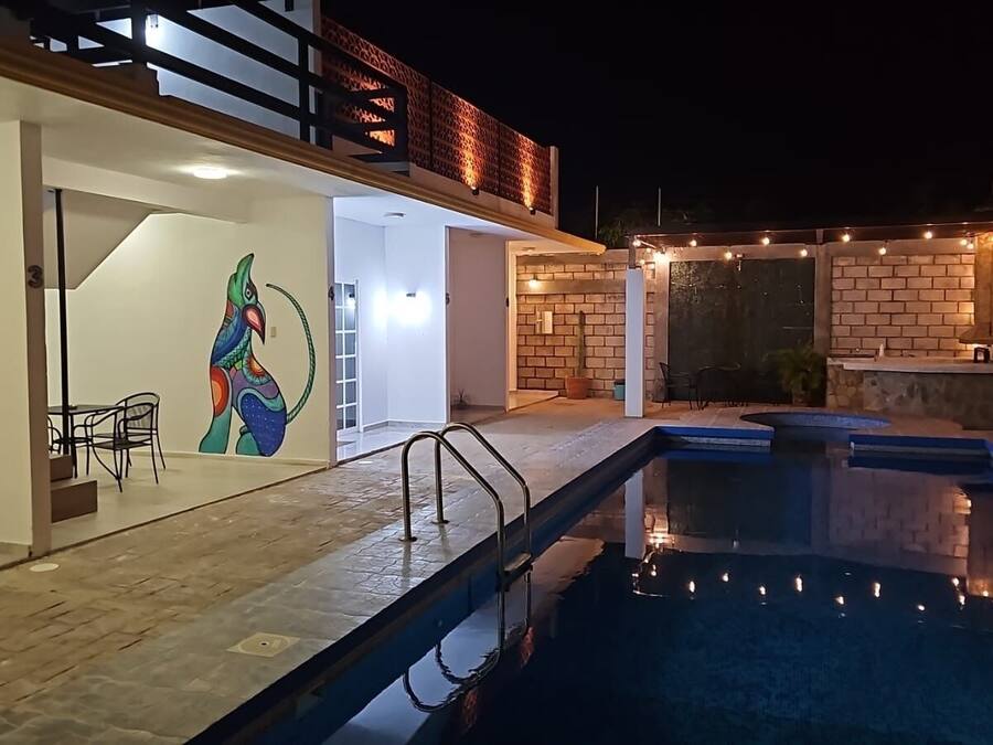A modern outdoor pool area with a clear view of the pool, a dining area with chairs, and a brick wall.