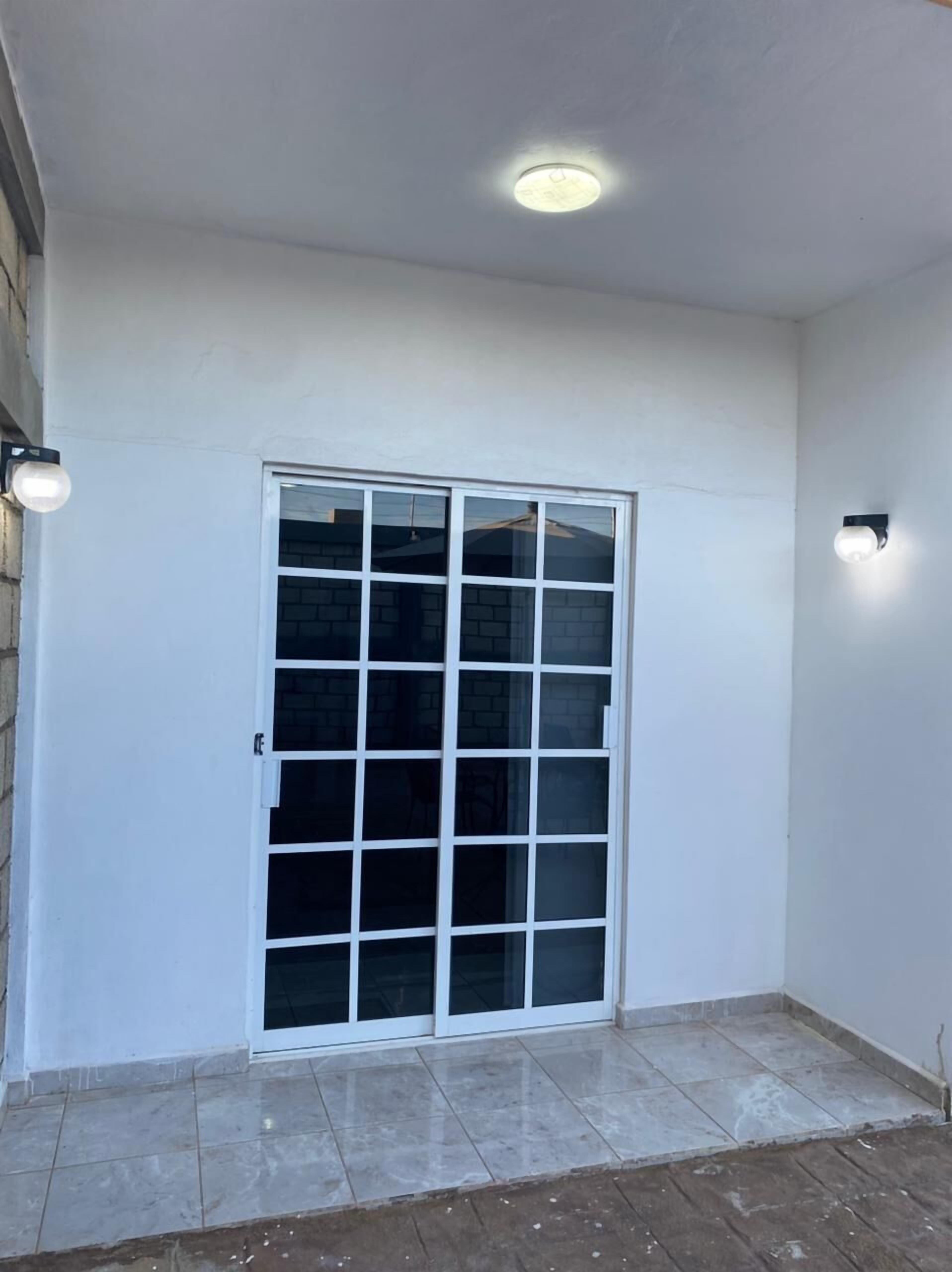 A room with a large sliding glass door, a ceiling light, and tiled flooring.