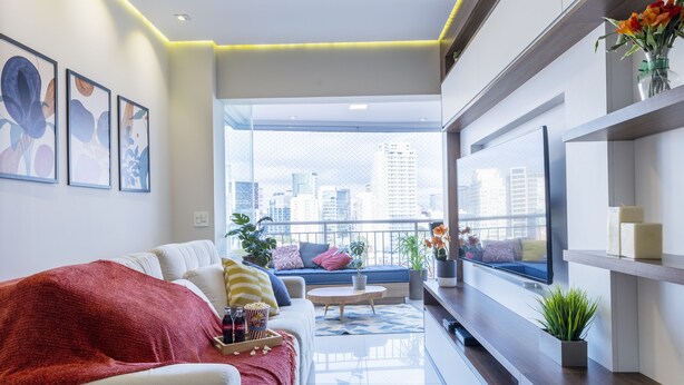 Una sala moderna con sofá, televisor y vista a la ciudad.